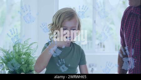 Image of handprints over caucasian boy brushing teeth Stock Photo