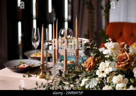 Festive wedding table for the newlyweds, decorated with compositions of fresh flowers and candles. Wedding decorations. Celebration in the banquet Stock Photo