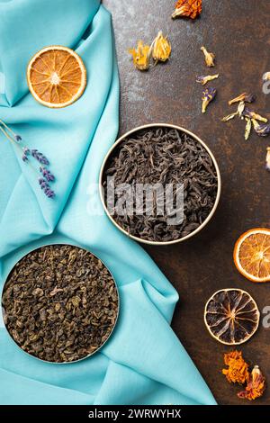Composition of black, green, flower tea and dried orange slices on blue and brown backgrounds top view. Large-leaf tea, dried flowers and citrus Stock Photo