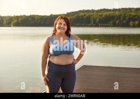 Happy overweight woman portrait near river, wearing sportswear top, heavy lady Stock Photo
