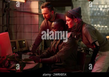 Group of three diverse people surviving apocalypse checking data on old computer in abandoned building Stock Photo