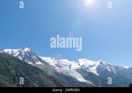 Backlight view with lens flares of the summit of Mont Blanc (4808 m), the highest mountain in the Alps, against blue sky in summer, Chamonix, France Stock Photo