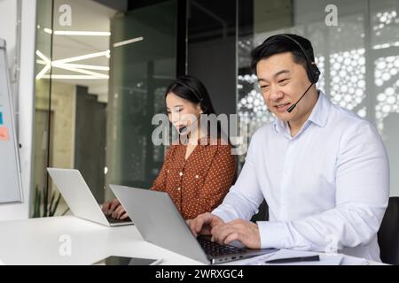 Focused professionals using laptops collaboratively in a well-lit contemporary office setting, embodying teamwork and efficiency. Stock Photo