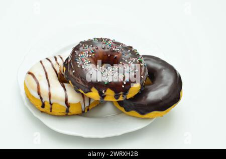 three assorted donuts on white plate, close up, isolated on white background Stock Photo