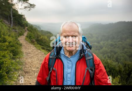 Senior backpacker hiking alone in beautiful landscape. Symbol for staying active at old age. Stock Photo