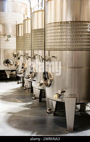 Modern stainless steel fermentation tanks used for wine production, highlighting the sleek, clean lines of a professional winery. Stock Photo