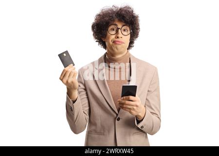Funny young man looking confused with a credit card and a smartphone isolated on white background Stock Photo