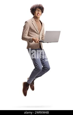 Excited young man holding a laptop computer and jumping isolated on white background Stock Photo