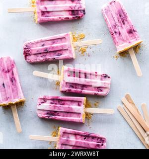 Homemade cherry yogurt popsicles scattered on a light rustic surface. Stock Photo