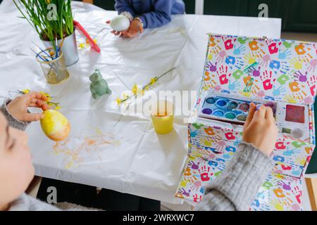 two siblings sitting at the table and painting easter eggs Stock Photo