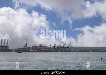 Cartagena, Colombia - July 25, 2023: Contecar container terminal with Hapag-Lloyd ship docked under blue cloudscape in Bahia de Cartagena de Indias Stock Photo