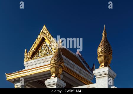 Detailed golden decorations at Wat Traimit (Temple of the Golden Buddha) in Bangkok, Thailand. Blue sky in the background. Stock Photo