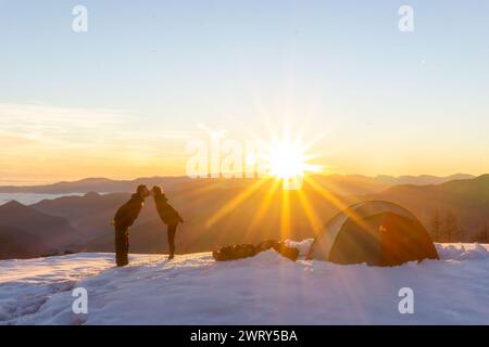 A couple kisses at sunset, camping in the snow. High quality photo Stock Photo
