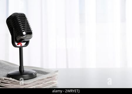 Newspapers and vintage microphone on grey table, space for text. Journalist's work Stock Photo