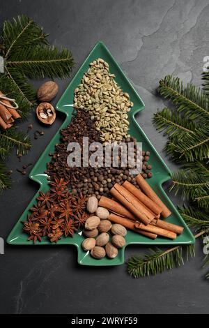 Different spices, nuts and fir branches on dark gray textured table, flat lay Stock Photo