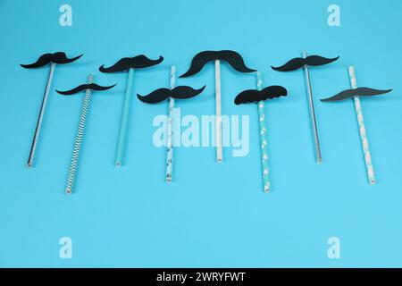 Fake paper mustaches with party props on light blue background Stock Photo