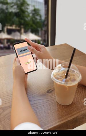 Cashback. Woman using smartphone at table indoors, closeup. Illustration of credit card and percent signs on device screen Stock Photo