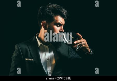 Cheerful bearded man is drinking expensive cognac. Old traditional whiskey drink - gentlemen beverage. Elegant and stylish man in classical wear Stock Photo