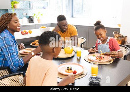 An African American family enjoys a breakfast together at home, vibrant kitchen setting Stock Photo