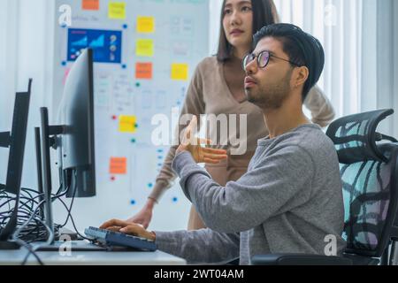 asian and Indian Developer team discussion feedback analysis coding data with software computer at office Stock Photo