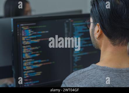 Asian prompt engineer developer coding app with software data sitting in front of computer monitor at office Stock Photo