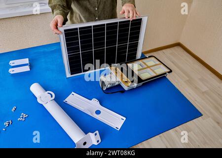 Eco-friendly street lamp with solar panel and LED lantern, woman mounts parts on bracket holder. Stock Photo