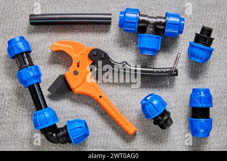 Compression fittings for water wastewater or irrigation lie on table next to pipe cutter. Stock Photo