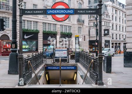 London streets at Piccadilly Circus. Entrance to London Underground with iconic sign and historic architecture. Stock Photo