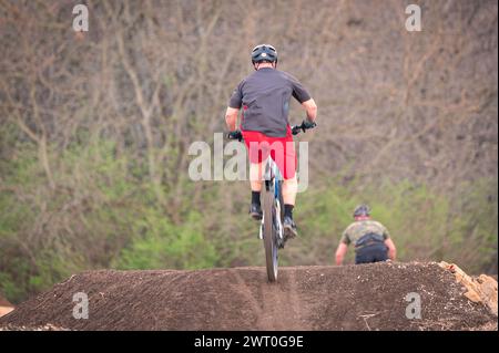 A person jumps a dirt bike with another rider in the background Stock Photo