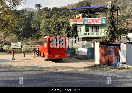 Red bus parked in front of a restaurant while people stand at a bus stop, Pokhara Valley, Pokhara, Nepal Stock Photo