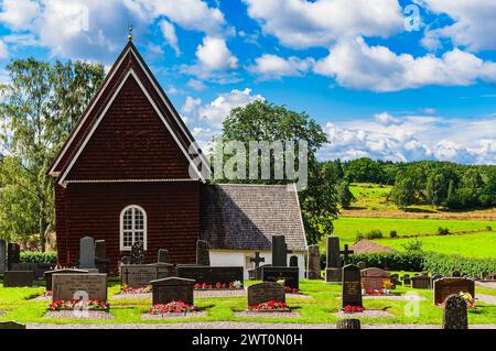 A church with a steeple stands tall against the sky, overlooking a cemetery with rows of headstones. The contrast between the spiritual and earthly re Stock Photo