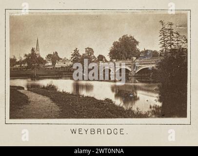 Weybridge. Henry W. Taunt, photographer (British, 1842 - 1922) about 1886 One of three tipped-in photographs illustrating a printed map of Shepperton, Sunbury, Walton-on-Thames, and the surrounding area along the River Thames. The photograph shows a view of the Wey Bridge over the River Wey. Town buildings line the bank on the far side of the river, including the Church of St. James, the tower of which can be seen through the trees. (Recto, mount) lower center, below image, printed in black ink: 'WEYBRIDGE.' Stock Photo