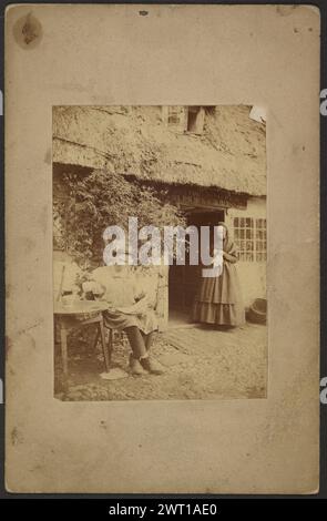 Man pouring beer at round table, woman standing, in front of tavern. John Whistler, photographer (British, 1830 - 1897) about 1855–1865 A man sitting at a table outside a pub pours beer out of a jug into his glass. A woman stands in the doorway sewing by hand. A sign for the pub hangs above her head. Stock Photo