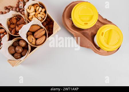 Two Takeaway Coffee Cups and a Variety of Nuts on a Bright Background. Stock Photo