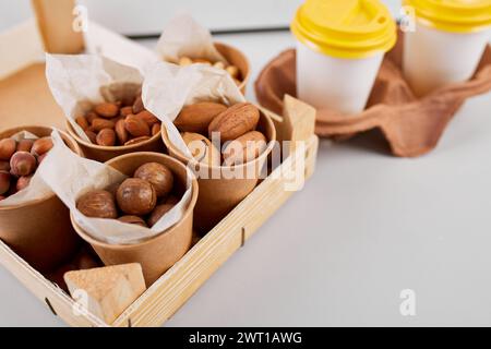 Two Takeaway Coffee Cups and a Variety of Nuts on a Bright Background. Stock Photo