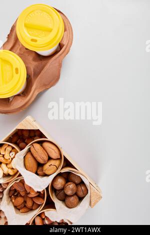 Two Takeaway Coffee Cups and a Variety of Nuts on a Bright Background. Stock Photo