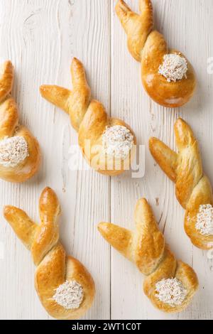 Background of Easter bunny buns with coconut closeup on a wooden table. Vertical top view from above Stock Photo