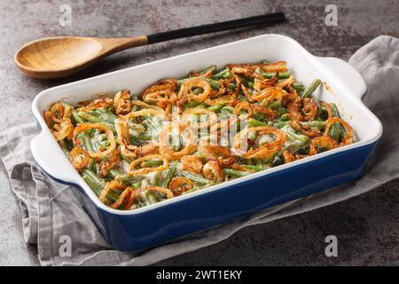 Green bean casserole with cheesy mushroom sauce and topped with crispy onions close-up in a baking dish on the table. horizontal Stock Photo