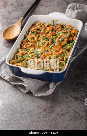 Close-up of Green Bean Casserole topped with crispy fried onions on the baking dish on the table. Vertical Stock Photo