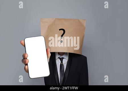 Anonymous person wearing blank empty paper bag on head and phone with empty display. App and cocial media concept Stock Photo
