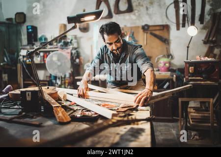 Focused craftsman measuring wood in his workshop, surrounded by tools of the trade. Stock Photo