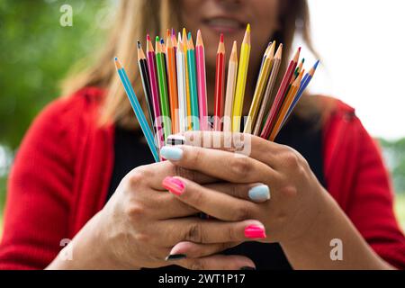 A hand holding a bunch of colored pencils Stock Photo