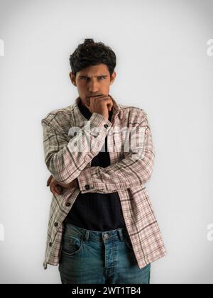 A man stands outdoors, deep in thought, with both hands resting on his chin. His eyes are fixated on something in the distance, lost in contemplation. Stock Photo
