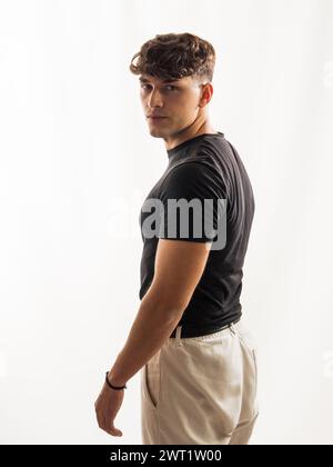 A man wearing a black shirt and khaki pants standing outdoors. He appears confident and focused as he poses for the camera. Stock Photo