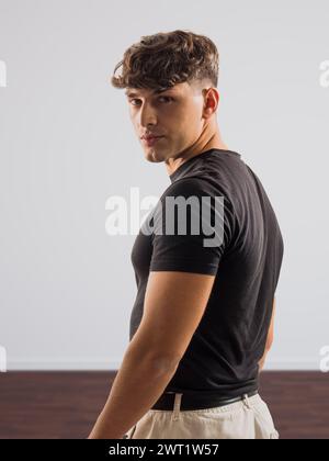 A man wearing a black shirt and khaki pants standing outdoors. He appears confident and focused as he poses for the camera. Stock Photo