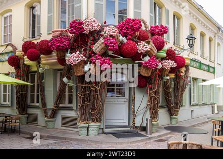 Vilnius, Lithuania - August 23, 2023, The entrance to a jewelry store in an old house is decorated with huge red artificial flowers and roses in wicke Stock Photo