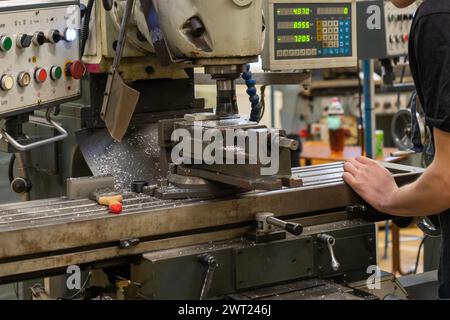 A worker works on a milling machine in a workshop Stock Photo