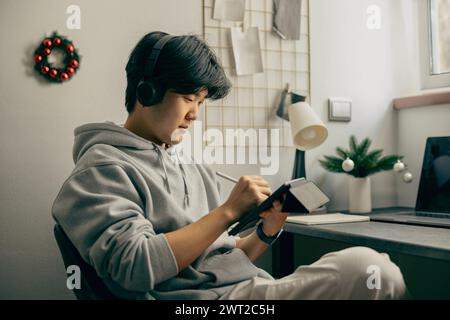 Focused male graphic designer in headphones use digital tablet for working from home office Stock Photo