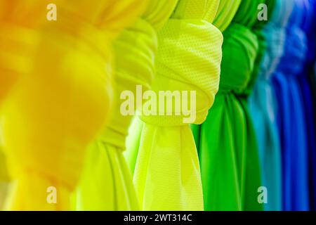 Collection of bright multicoloured folded textile sheets, shawls or scarves, abstract clothes background Stock Photo
