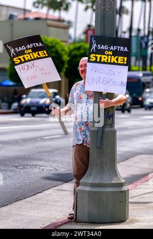 A SAG-AFTRA actor holds two pickets signs up while facing traffic near the picket line during the writers and actors strike in front of Paramount Stud Stock Photo
